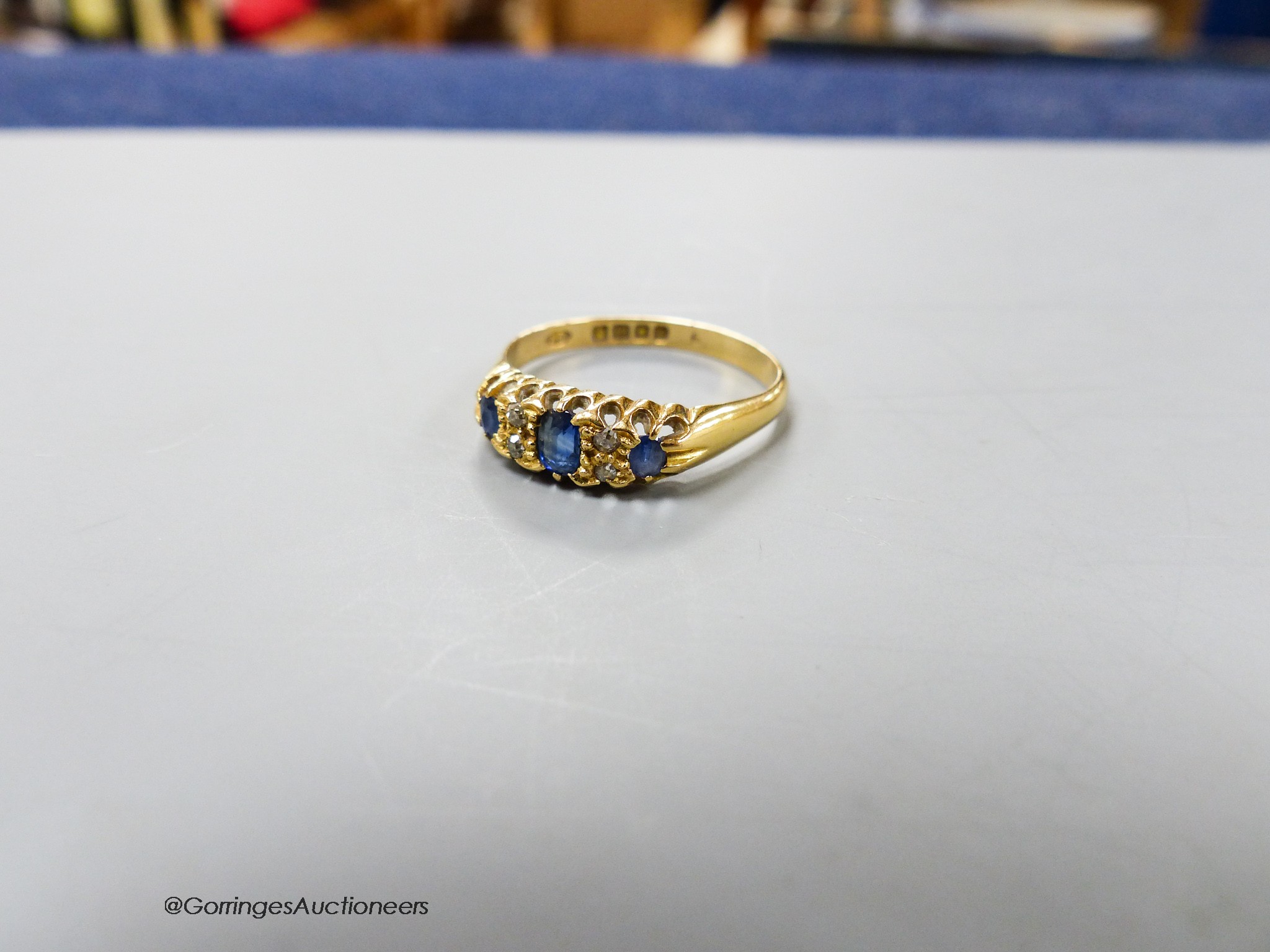 An Edwardian 18ct gold, three stone sapphire and diamond chip set ring, size R, gross weight 3.1 grams.